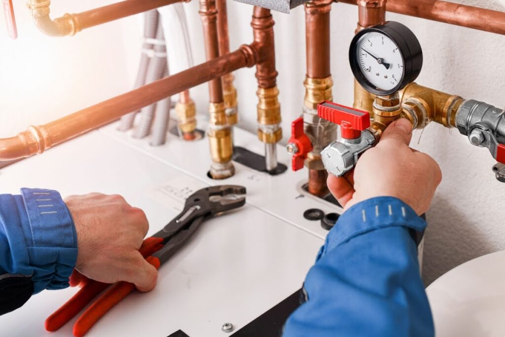 Plumber's hands adjusting water heater pipes during a routine maintenance