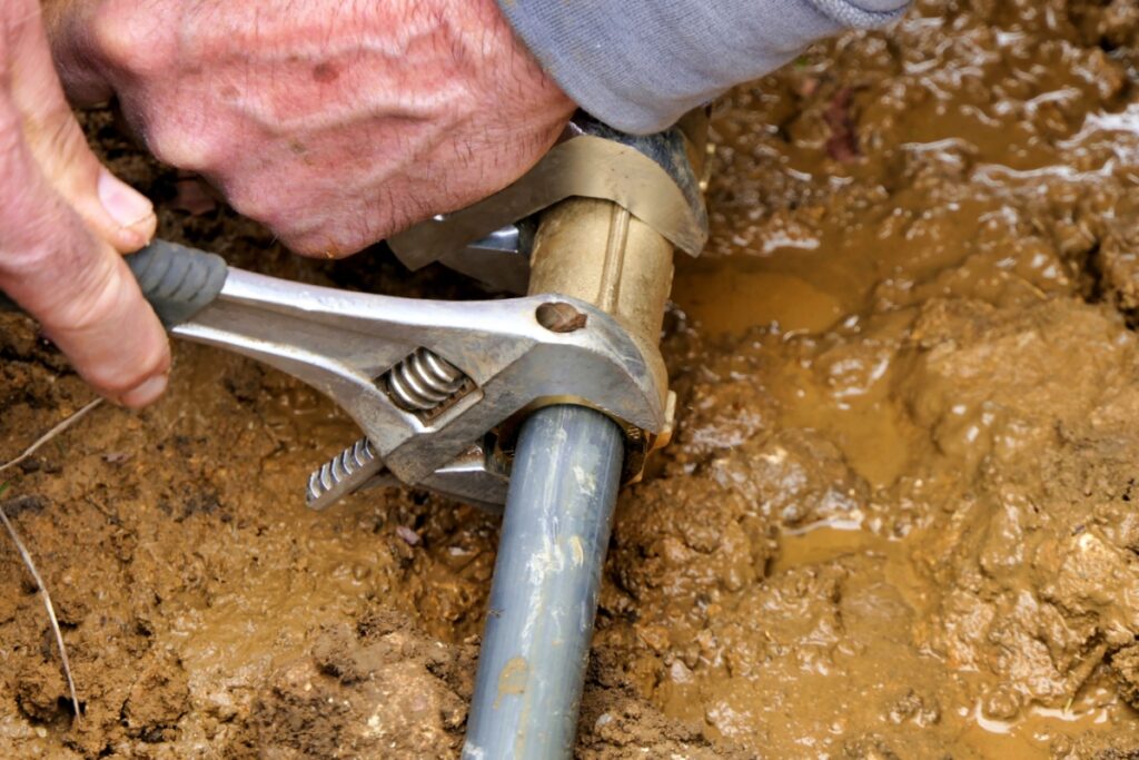 plumber trying to fix a broken underground pipe that is leaking water